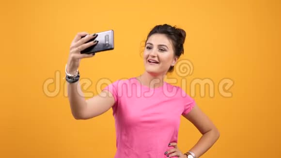 一位穿着粉色t恤的快乐微笑女人在自拍视频的预览图