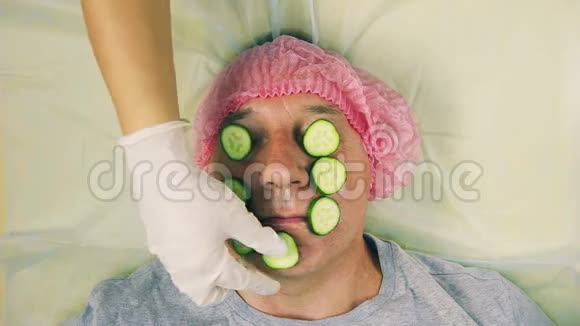 美容师的手把男人的脸从黄瓜上移开视频的预览图