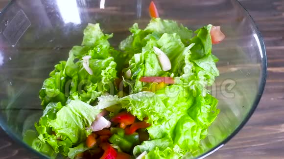 厨师用橄榄油浇沙拉在一个大玻璃杯里一股薄薄的油倒在新鲜的天然蔬菜沙拉上视频的预览图