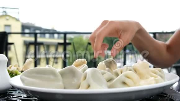女人用手在盘子里端着菜饺吃视频的预览图
