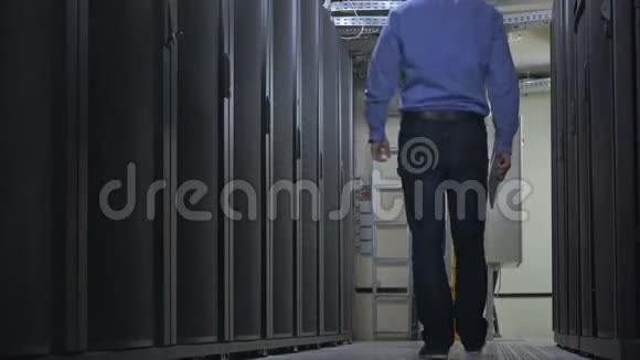 IT工程师穿着一件带记事本的蓝色衬衫在服务器机房打开服务器机柜视频的预览图