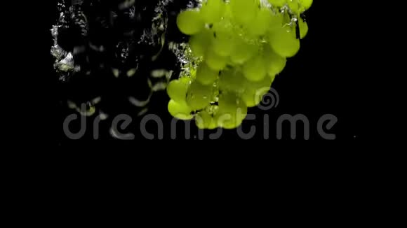绿色和蓝色葡萄枝在黑色背景的透明水中落下视频的预览图
