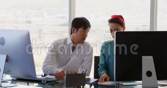 混合种族商务人员在办公室办公桌上通过电脑讨论的前台视图视频的预览图