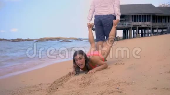 男人拉着一个女孩沿着海岸女孩抗拒并想进一步休息假期结束的概念视频的预览图