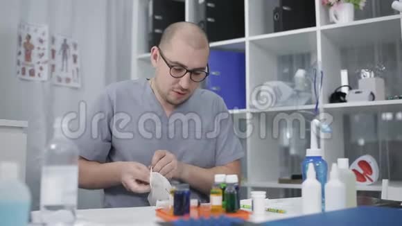 一位戴眼镜的实验室技术人员戴上橡胶手套诊所的实验室研究视频的预览图