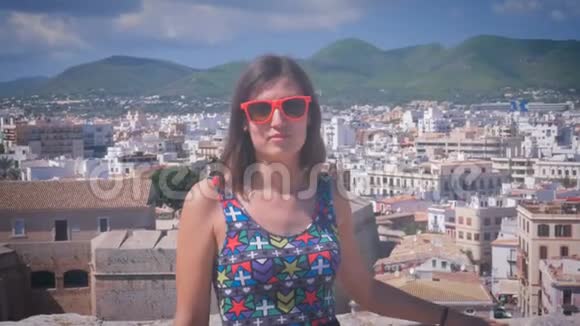 在伊比萨镇的达尔特维拉戴着甜眼镜的美丽年轻女孩微笑着Eivissa老城视频的预览图