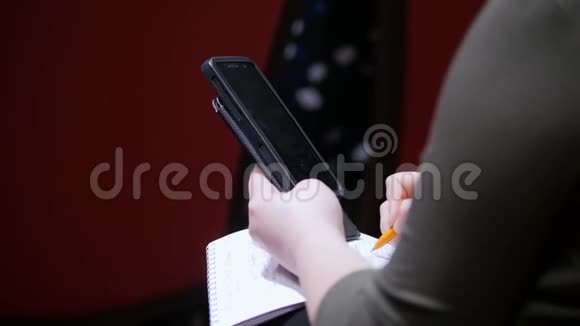 厅的商务会议一个人坐在讲座上在笔记本上做记号拿着一个视频的预览图