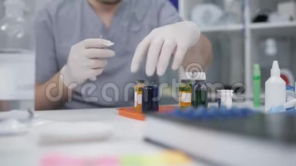 一位戴眼镜的实验室技术人员在餐桌上将液体试剂从小瓶中拨入注射器实验室研究视频的预览图