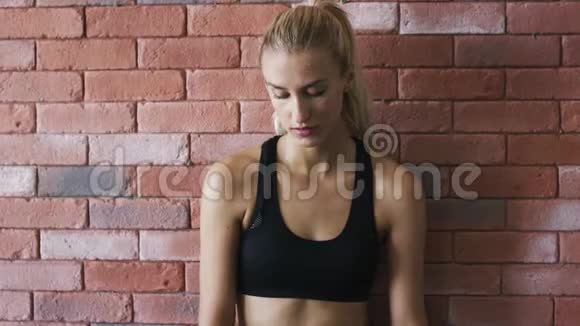 积极的女运动员靠在砖墙上视频的预览图