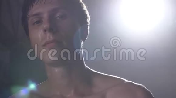 年轻挥汗如雨的拳击手戴着手套摸着他的头看着摄像机视频的预览图