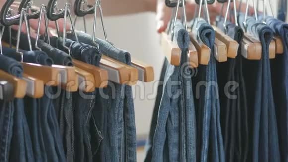 各种各样的女人牛仔裤挂在衣架上女人在商店里挑选衣服双手合拢视频的预览图