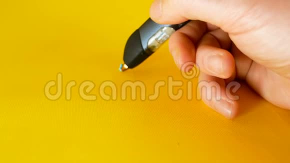 一个男人用3D打印笔在黄色背景上画一座小房子这是一个理想的主题如视频的预览图
