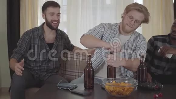 三个快乐的年轻朋友一起喝啤酒在家聊天视频的预览图