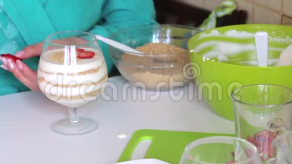 女人用草莓片装饰甜点玻璃层里铺着饼干碎屑和奶油从上面的草纸上视频的预览图