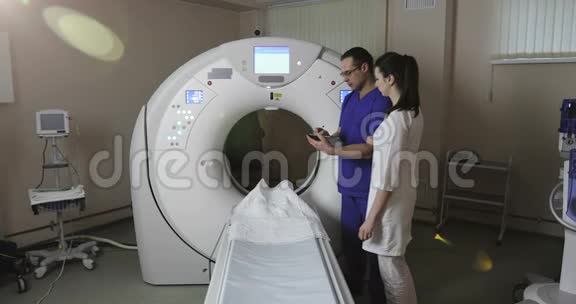 4两位医生在一家新现代癌症治疗医院的CT扫描室讨论病人的病史视频的预览图