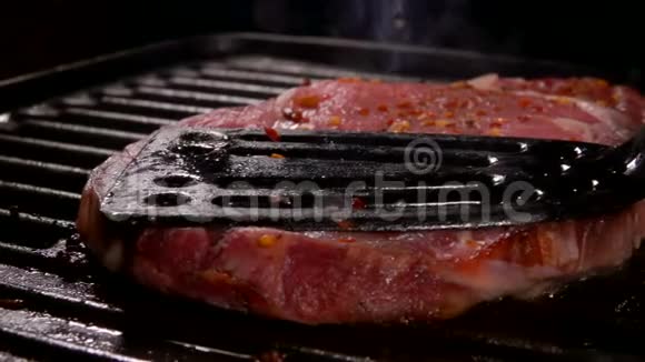 牛排用厨房的铲子压在烤架上视频的预览图