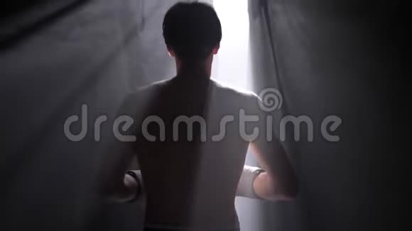 戴着手套的无衫拳击手打电话来等着在黑暗的房间里抽烟视频的预览图