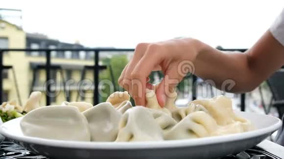 年轻女子用手在餐馆里端着盘子吃卡卡利视频的预览图