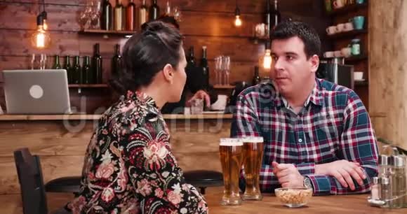 白种人夫妇在老式酒吧或餐馆喝啤酒和吃花生视频的预览图