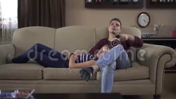 家里的一对恩爱夫妻躺在电视机前的床上视频的预览图