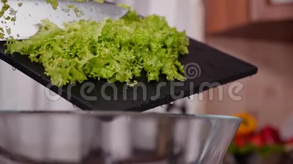 女人用手把生菜从砧板上塞进碗里视频的预览图