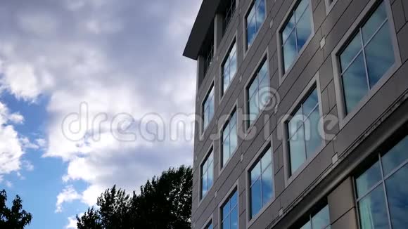 多云的天空现代办公大楼上有明亮的反射玻璃立面视频的预览图