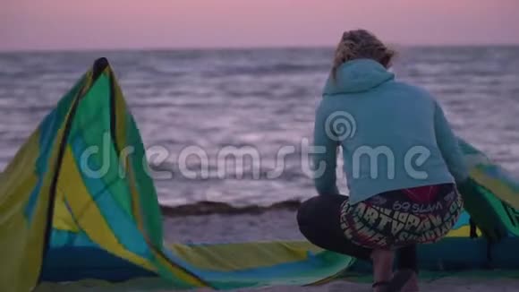 女人坐在沙滩上调整她的训练风筝视频的预览图