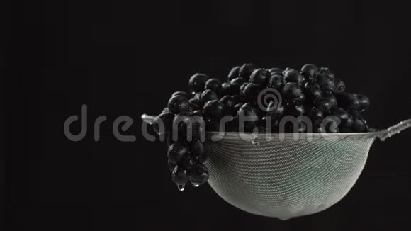 在视频中我们看到葡萄在筛子里水从顶部开始下落相机从左向右移动黑色视频的预览图