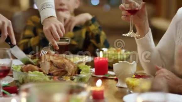 一个男人在圣诞家庭餐桌上切鸡腿老太太在等他视频的预览图