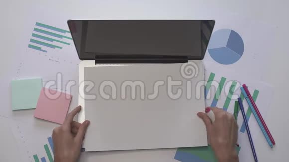 女人在笔记本电脑上的一张纸上写HACKING带有图表的办公桌面视频的预览图