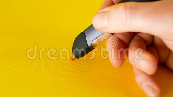 一个人的手用3d打印笔在黄色背景上写钱这是拍摄诸如视频的预览图