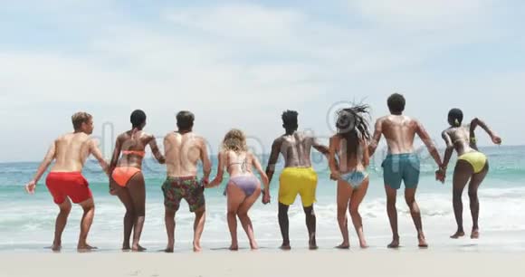 混合种族朋友在海滩上跳跃的正面景色视频的预览图