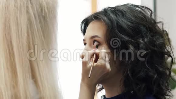 美丽的女人化妆艺术家描绘一个迷人的年轻不伦黛的眼睛视频的预览图
