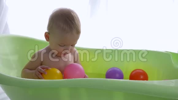 儿童卫生可爱的小男孩在明亮的房间里游泳时玩彩球视频的预览图