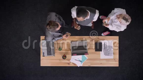 三个穆蒂族的工人正拿着一杯香槟站在桌子旁办公室里放着笔记本电脑公司聚会视频的预览图