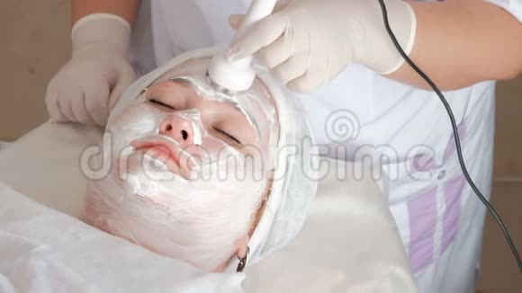 超声波面部皮肤提升的程序在一个胖女孩脸上抹一层白色营养霜视频的预览图