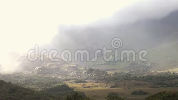 光线穿透云层和雾气照射在山谷中的岩石上视频的预览图