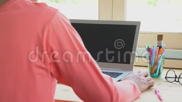 橙色T恤商人点击鼠标或在笔记本电脑前工作视频的预览图