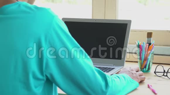 绿色T恤商人点击鼠标或在笔记本电脑前工作视频的预览图