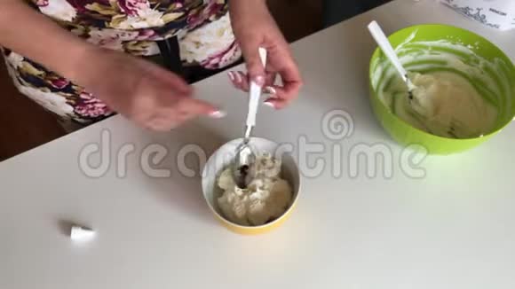 女人用勺子混合软奶酪为蛋糕准备奶油添加了食用色素视频的预览图