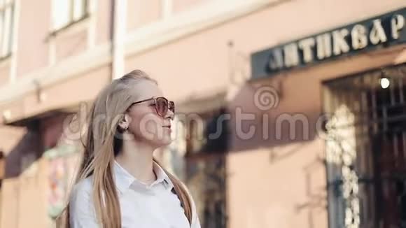 戴太阳镜的漂亮模特步行穿过城市看着城市的郊区视频的预览图