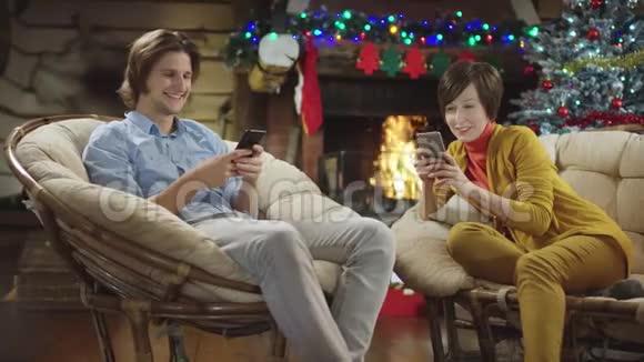 母亲和儿子在圣诞节晚上用智能手机上网笑了视频的预览图