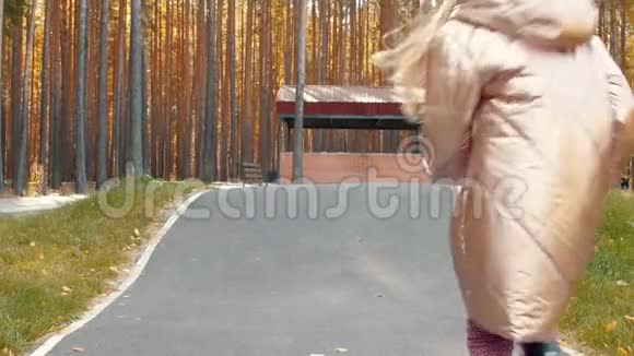 穿着暖和的夹克和帽子的嬉戏的女孩在秋天公园的路上离家出走视频的预览图