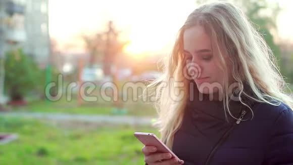 一个年轻的女孩站在街上手里拿着一部智能手机视频的预览图
