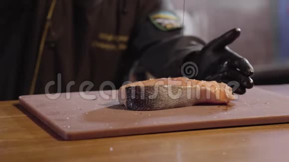 厨师用手把一大块三文鱼的油灌起来穿黑色长袍和橡胶手套的人做菜准备食物视频的预览图