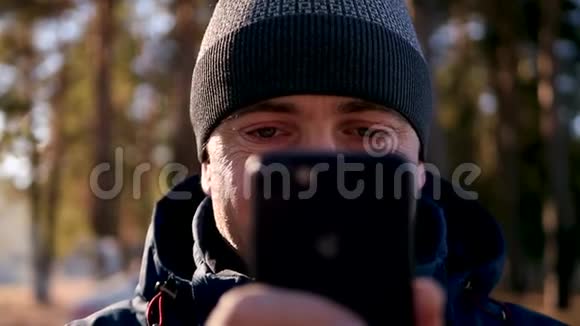 一个穿着温暖衣服的男人在寒冷的季节用智能手机看着手机屏幕特写镜头视频的预览图