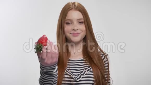 年轻甜美的姜姑娘带着草莓微笑白色的背景视频的预览图