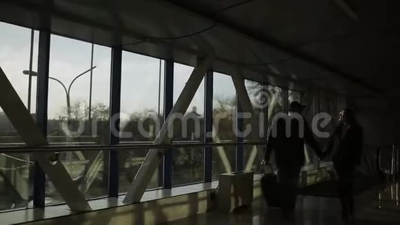 美丽的年轻夫妇在机场日落时走到行李架上视频的预览图