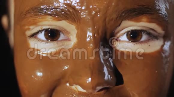 带着巧克力面膜的年轻女孩的脸视频的预览图
