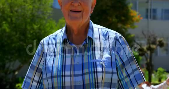 积极的高加索老人站在养老院花园的正面景色视频的预览图